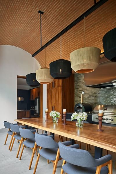 Casa Campanas dining room with a long wooden table under woven pendant lamps at Singular Signature Residences