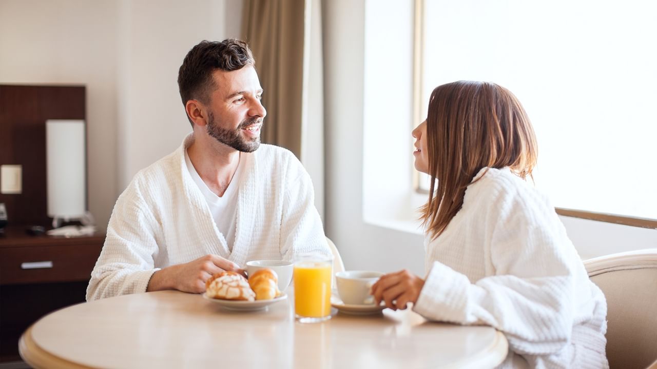 a happy couple enjoying breakfast in a hotel room