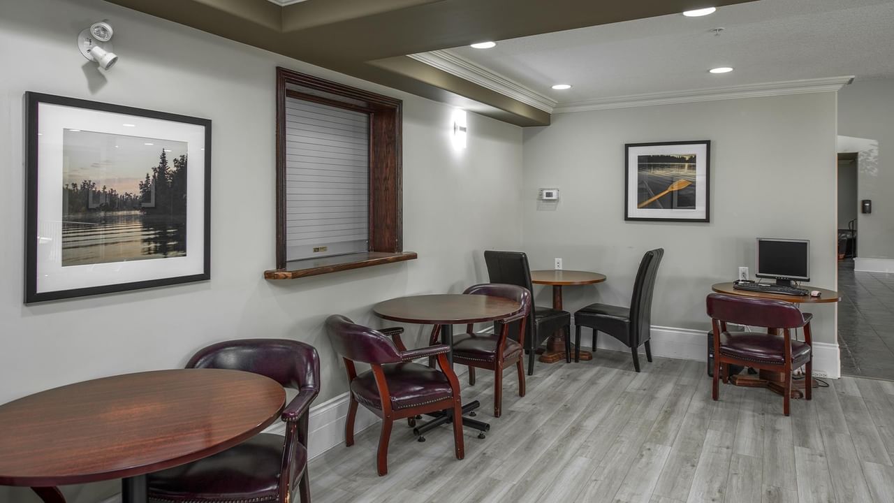 Business center with wooden tables, leather chairs, and framed landscape artwork at Coast Edson Hotel