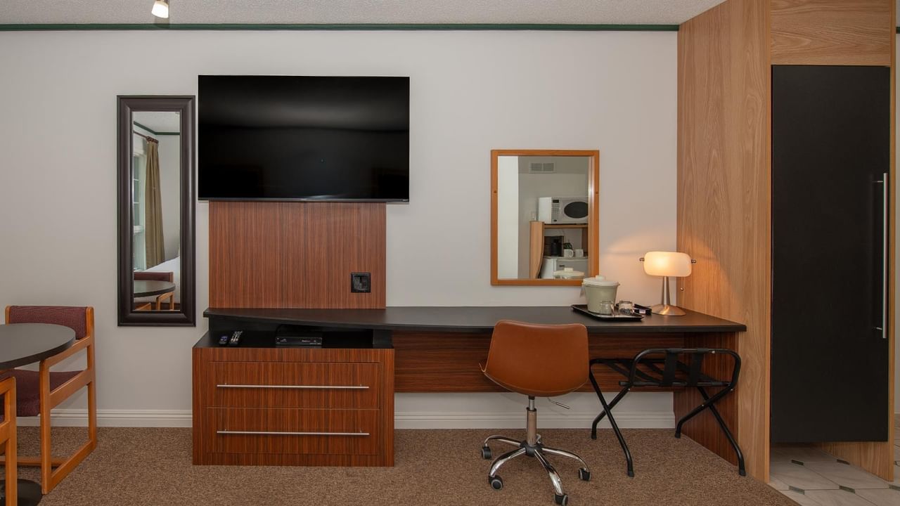 guest room area with TV, dresser, desk and chair at Coast Whitecourt Hotel