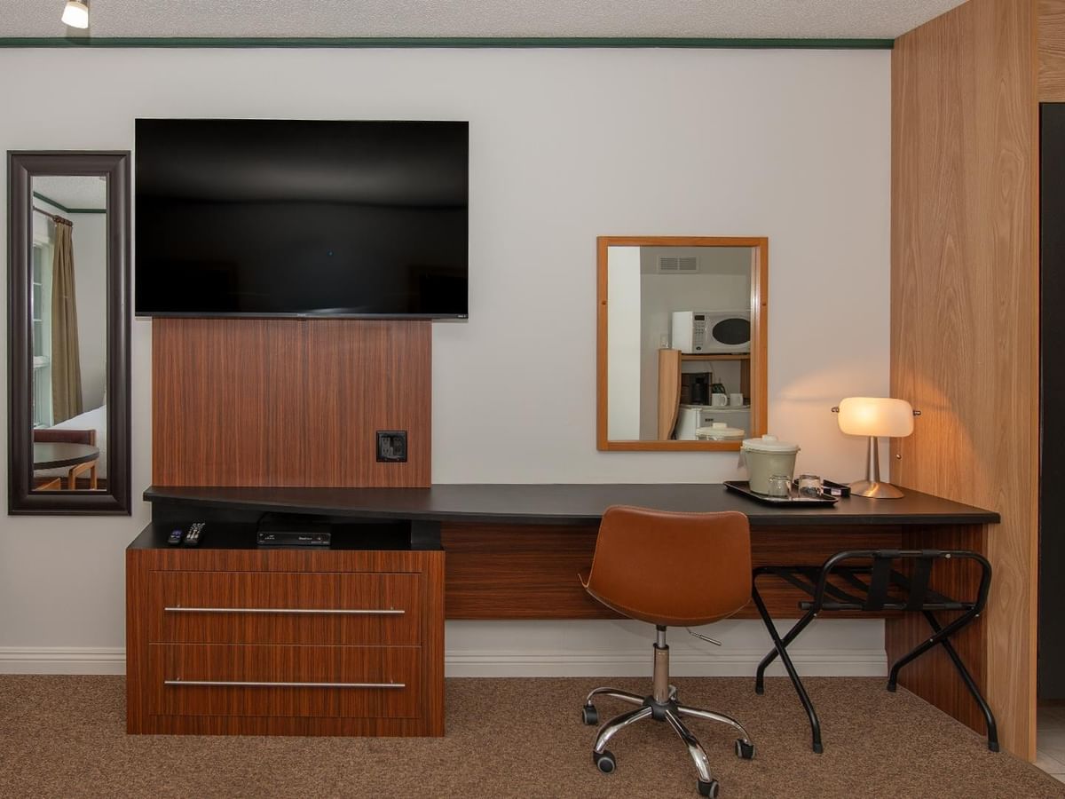 Guest room entertainment area with a wall-mounted TV, desk, chair and wardrobe
