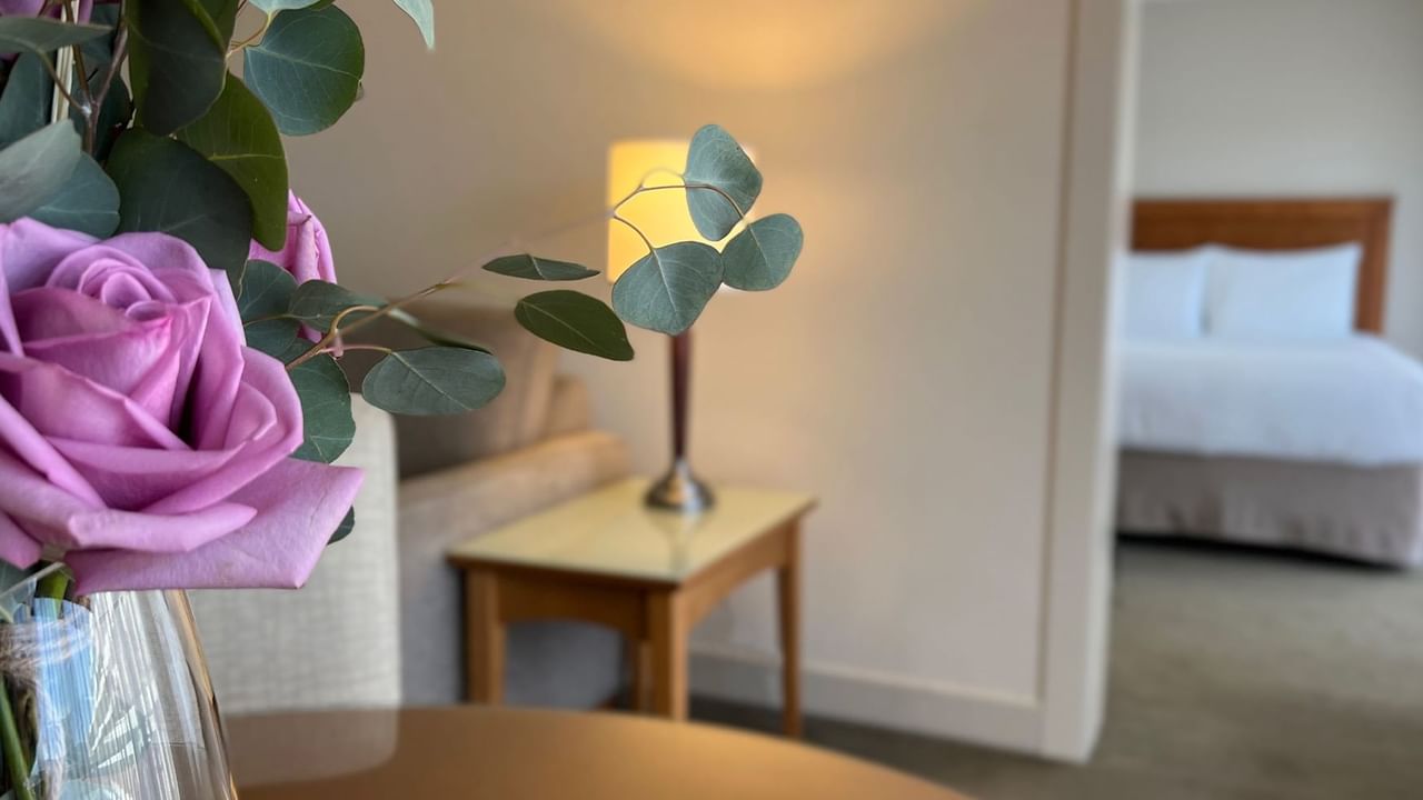 Up close shot of roses in vase with guest room in backround