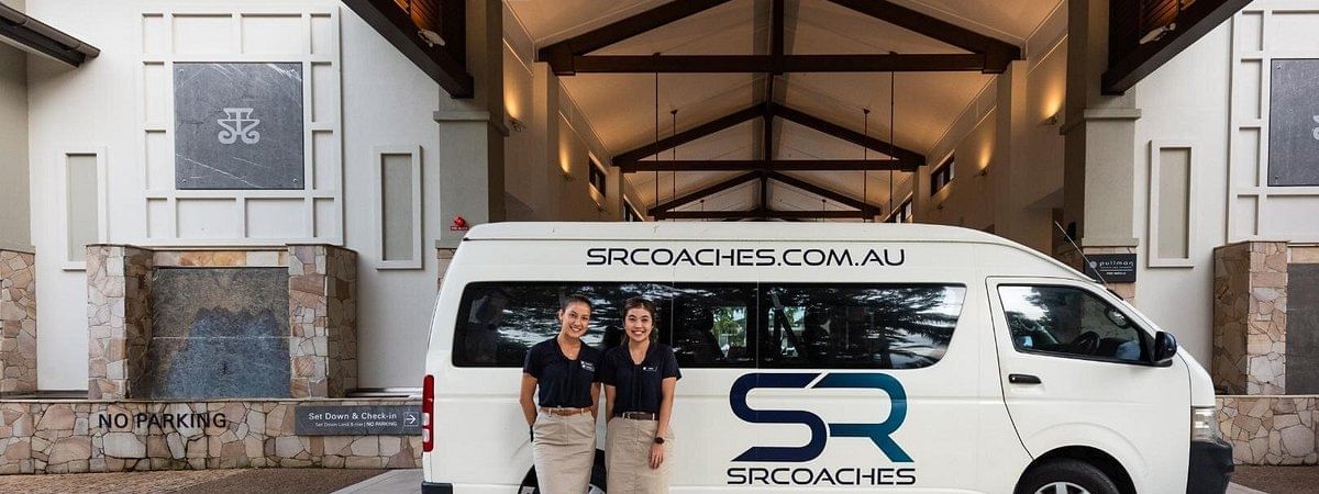 Shuttle van parked in front of entrance with two people standing beside it at Pullman Port Douglas