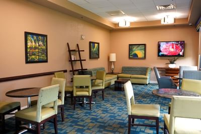 TV, paintings, and chairs in the lounge area at Rosen Inn International