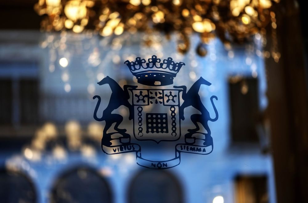 Hotel Westminster Paris crest with mythical beasts printed on glass, set under a glowing crystal chandelier