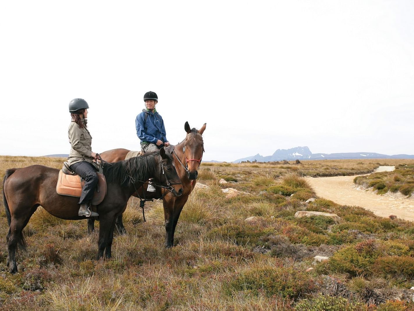 Man and a woman riding horses near Cradle Mountain Hotel