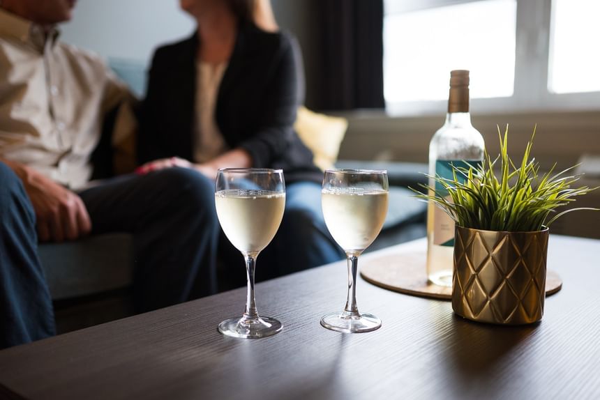 Wine glasses on a dark coffee table by a potted plant at Rodd Miramichi River, a featured Miramichi hotel