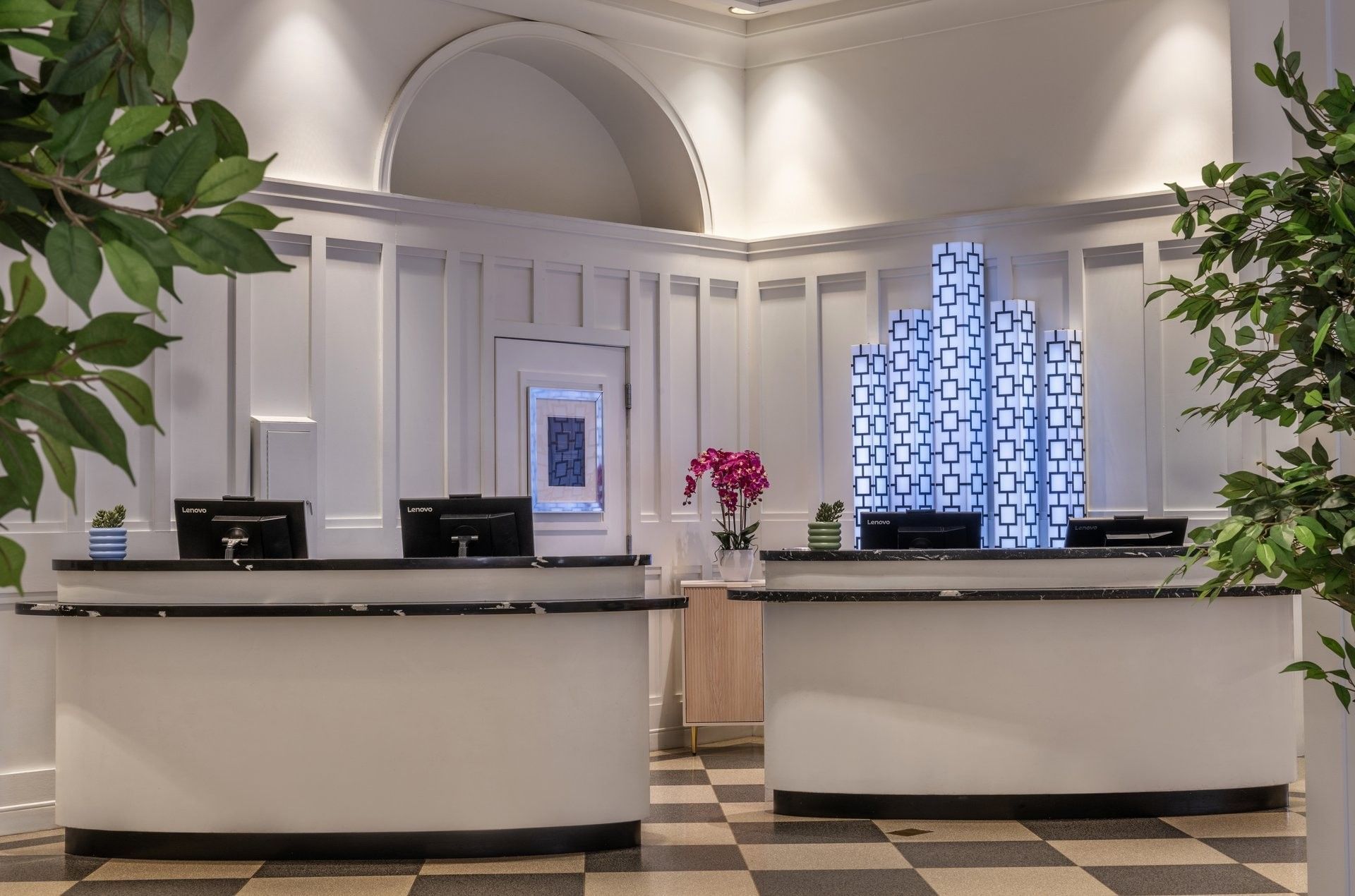 Reception desks placed by white paneled walls under decorative illuminated art at Warwick Allerton Chicago