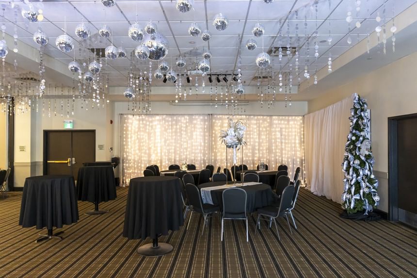 Event tables by a Christmas tree under hanging disco balls, with a string light backdrop at Rodd Miramichi River