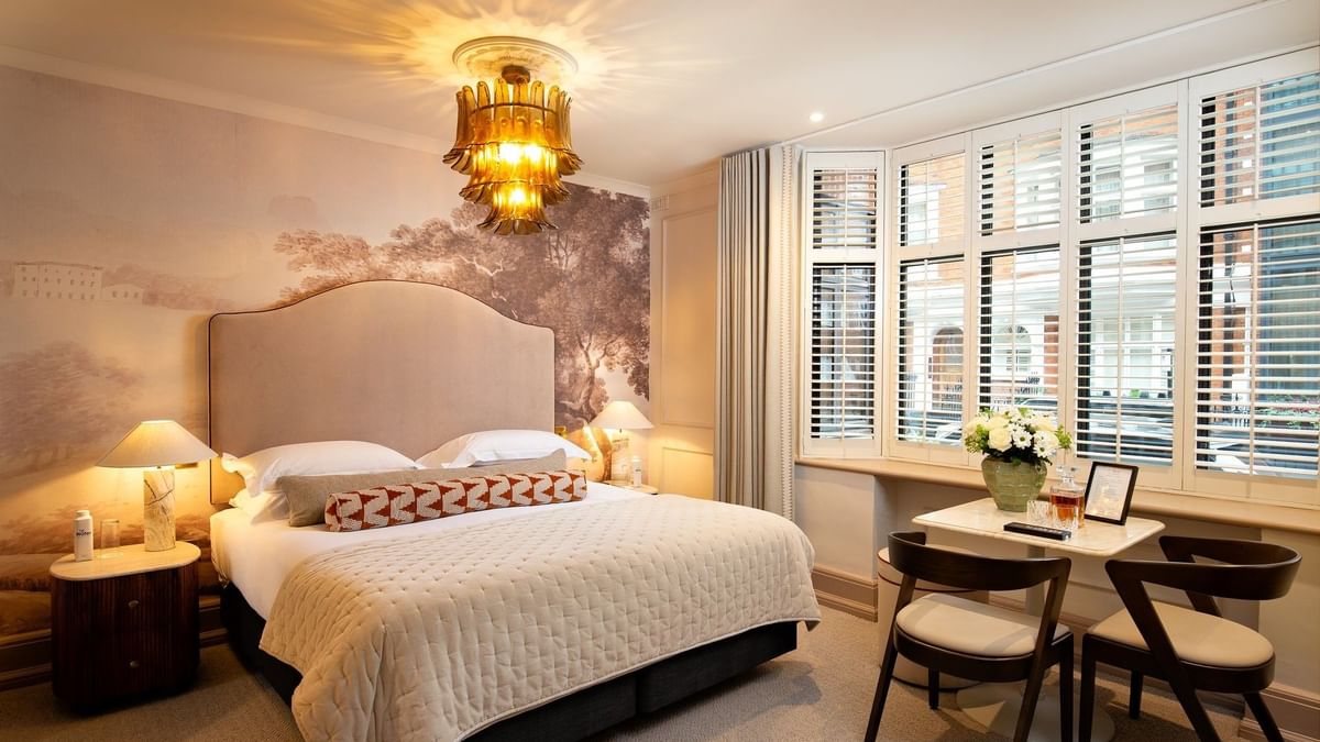 Bed with side tables and a working desk near window in Studio Apartment at The Capital Hotel, Apartments and Townhouse