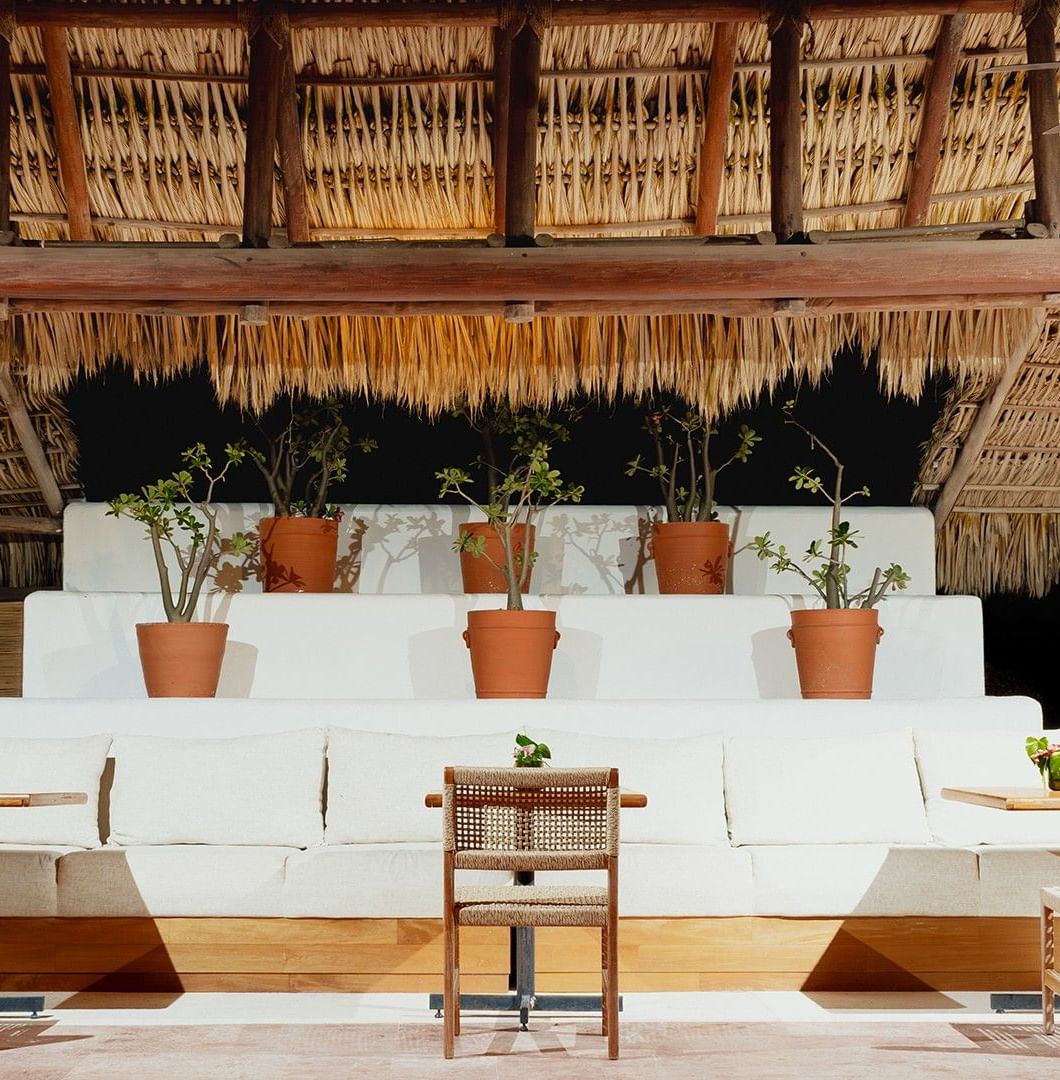 Dining area with woven chairs, a cushioned seating area, & thatched roof in Camino Real Club at Camino Real Zaashila Huatulco