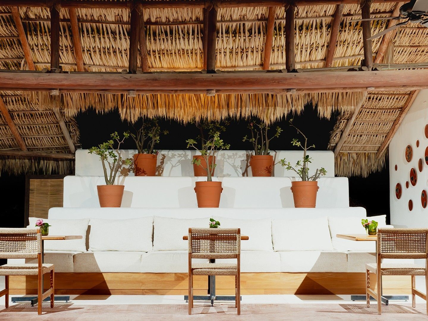 Dining area with woven chairs, a cushioned seating area, & thatched roof in Camino Real Club at Camino Real Zaashila Huatulco