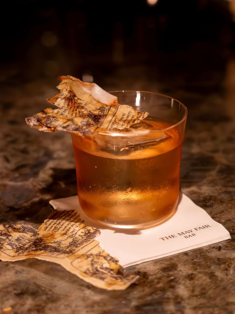 A cocktail glass of Lomond with edible poetry at The May Fair Bar