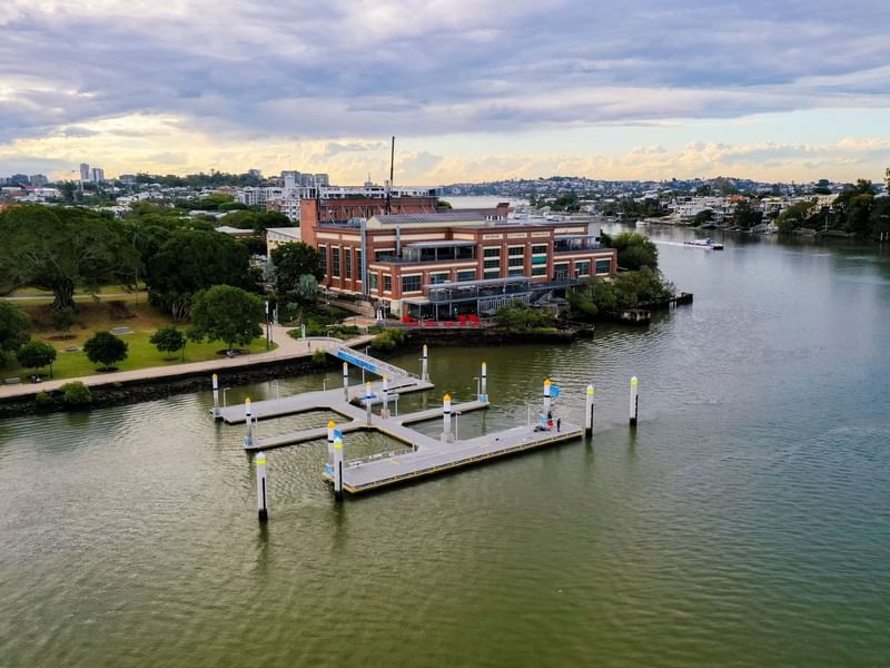 Aerial view of Brisbane Powerhouse by a river with cityscape near Sofitel Brisbane Central
