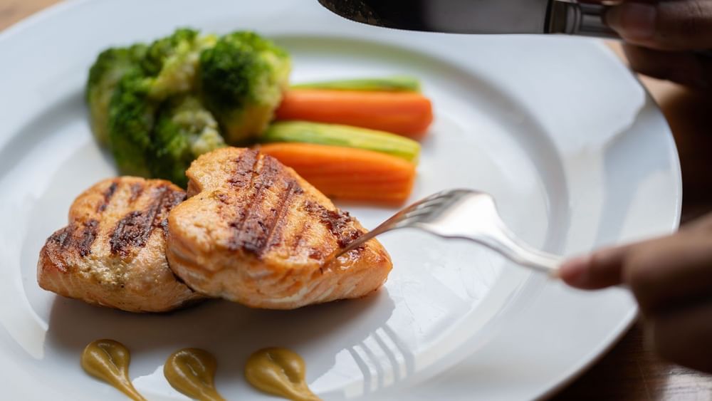 Grilled heart-shaped salmon fillets served alongside steamed broccoli & carrots in Seasons Restaurant at Warwick Hotel Jeddah