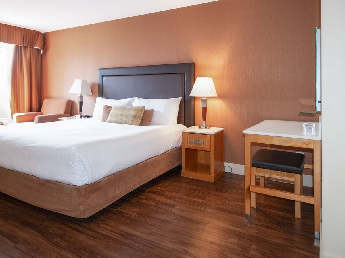 Hotel room with king bed, nightstands, lamps and work desk