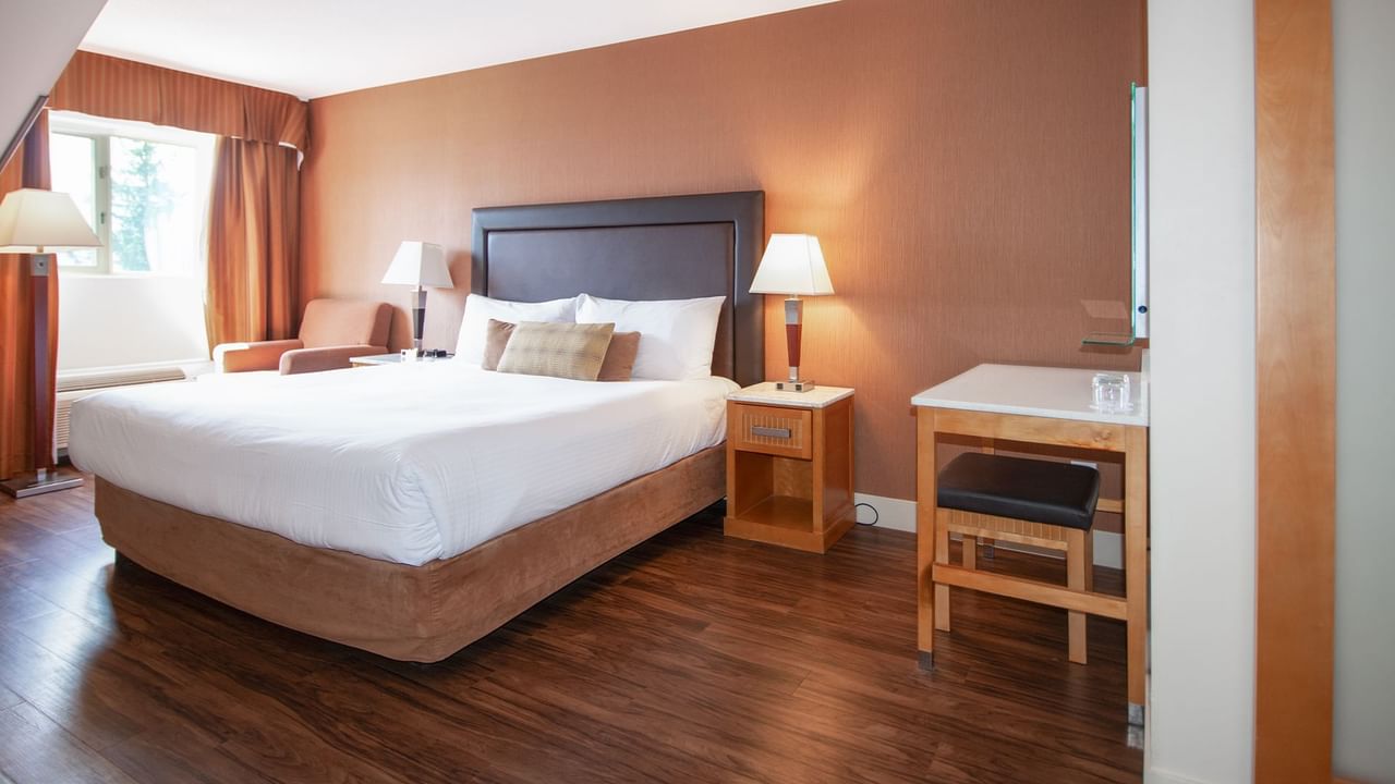 Hotel room with king bed, nightstands, lamps and work desk