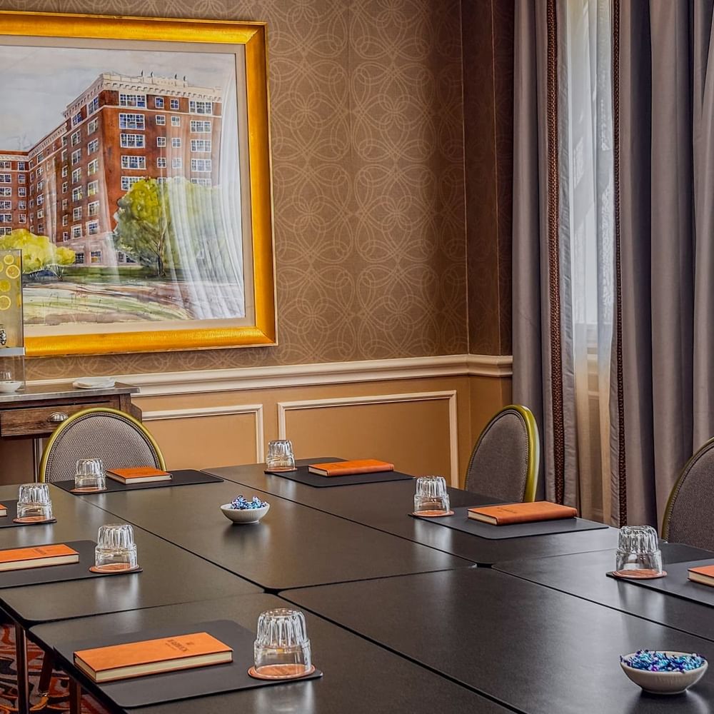 Black table by grey chairs under a large painting in Cedar Springs at Warwick Melrose Dallas