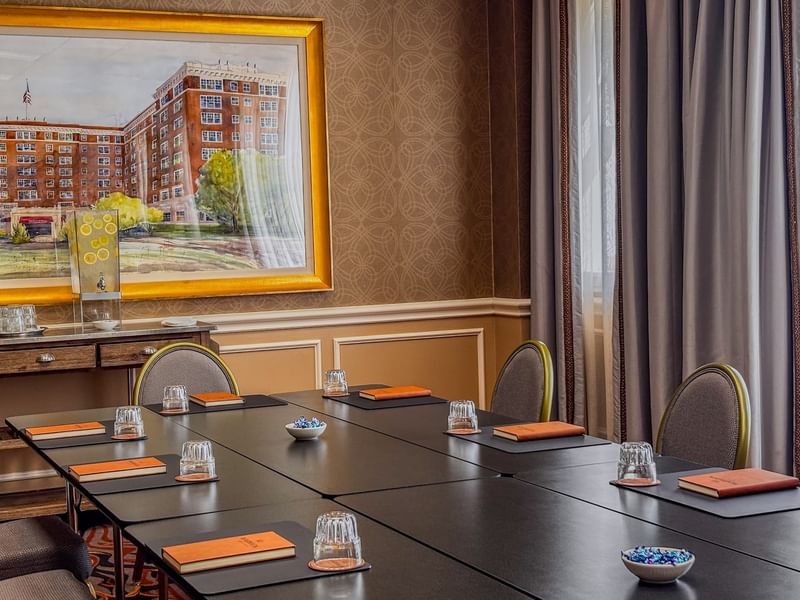 Black table by grey chairs under a large painting in Cedar Springs at Warwick Melrose Dallas
