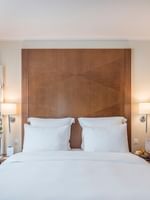 King bed with a wood headboard by small side tables under glowing wall lamps in Classic Room at Warwick Geneva