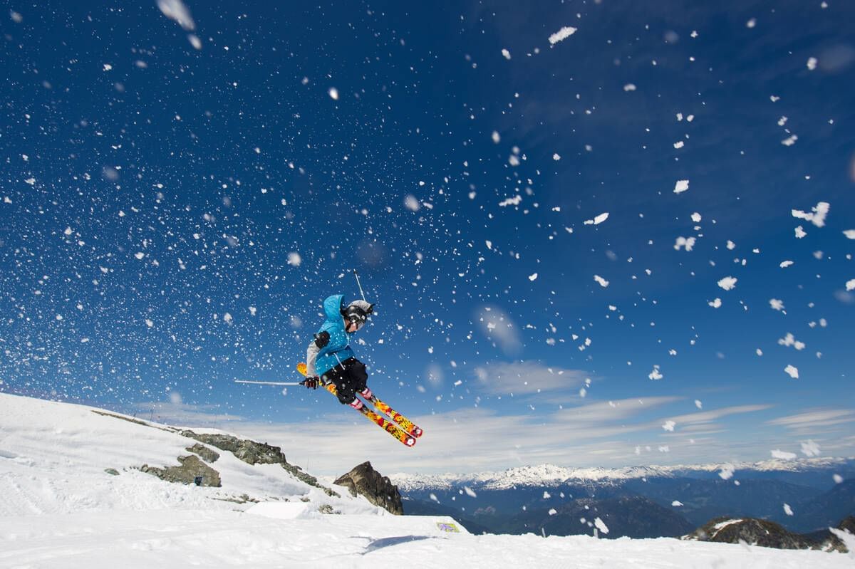 Skier jumping over snowy hills near Blackcomb Springs Suites