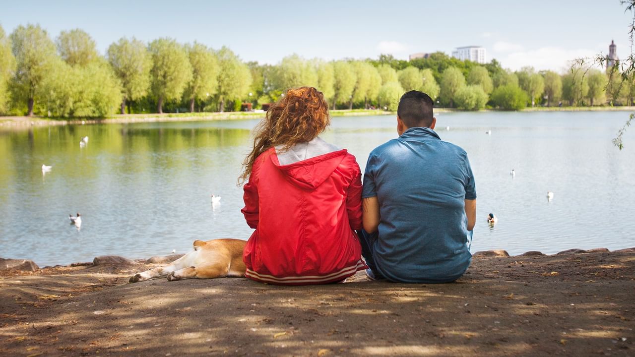 Couple and dog sitting by a lake