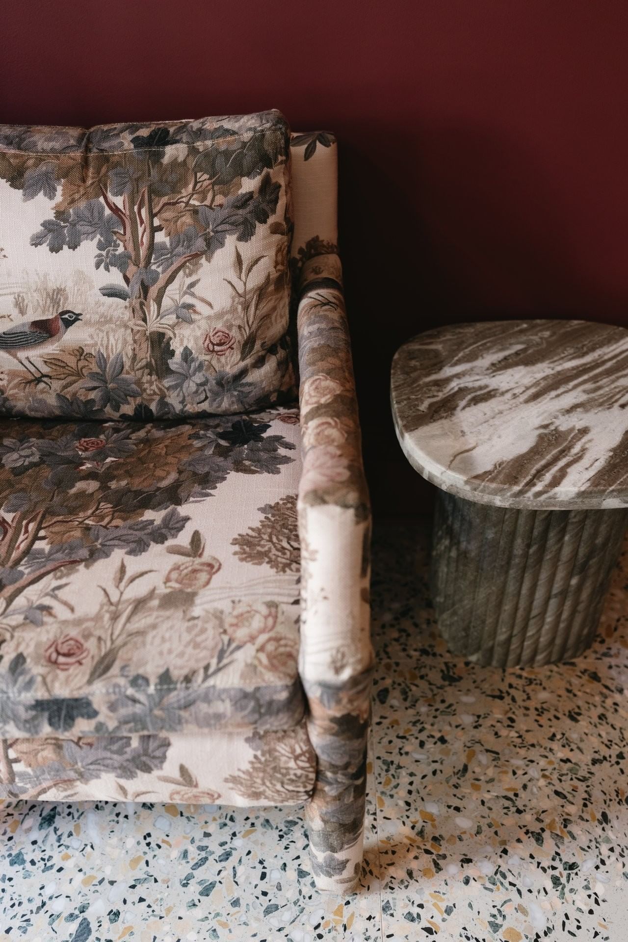 a floral armchair and a marble side table in a lobby