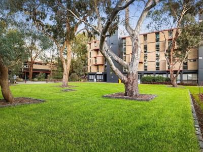 Green lawn with trees in front of La Trobe University – Menzies College.