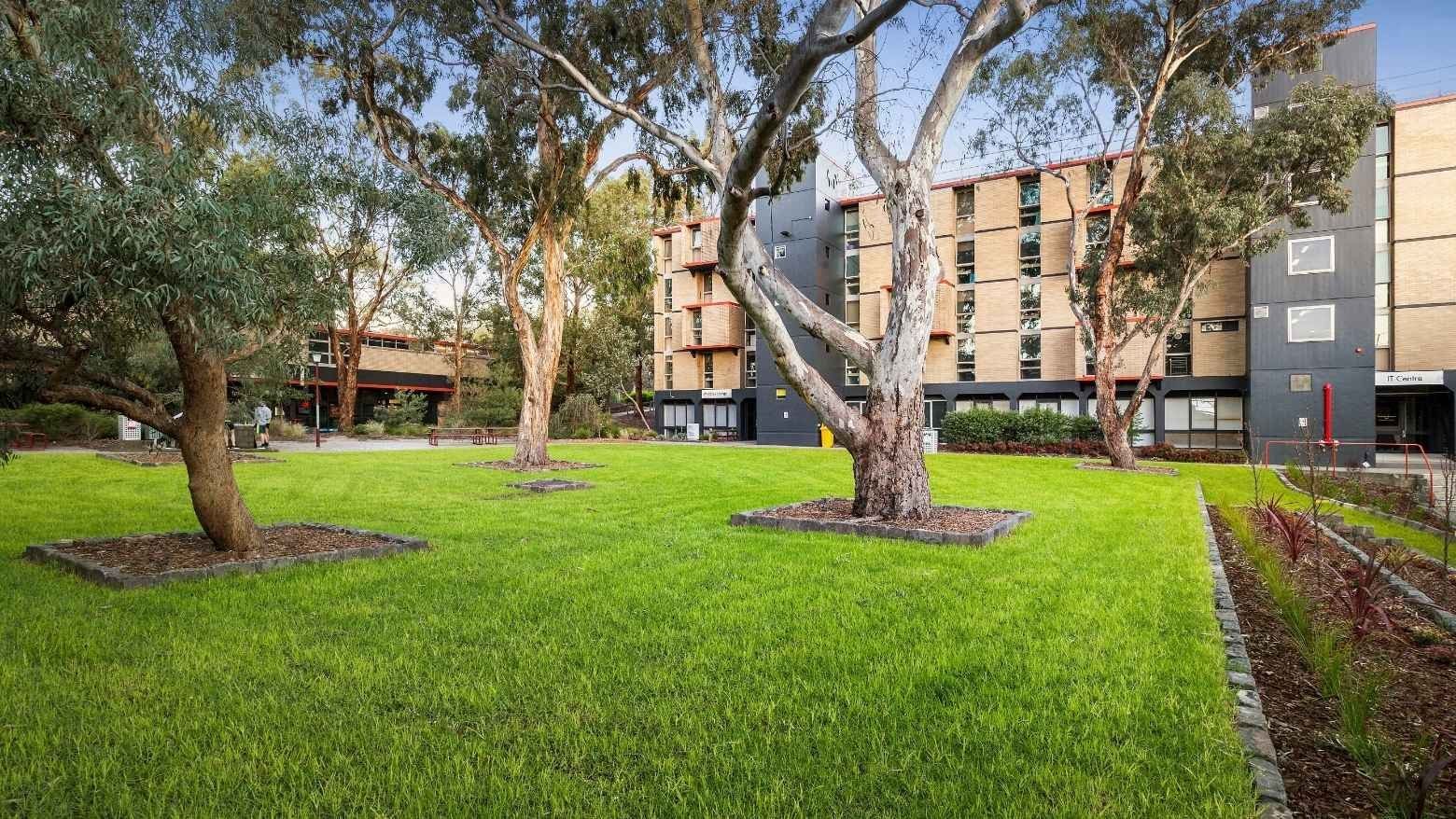Green lawn with trees in front of La Trobe University – Menzies College.
