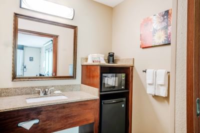 Guestroom vanity area with granite countertop, microwave, mini-fridge, and coffee station at Rosen Inn International