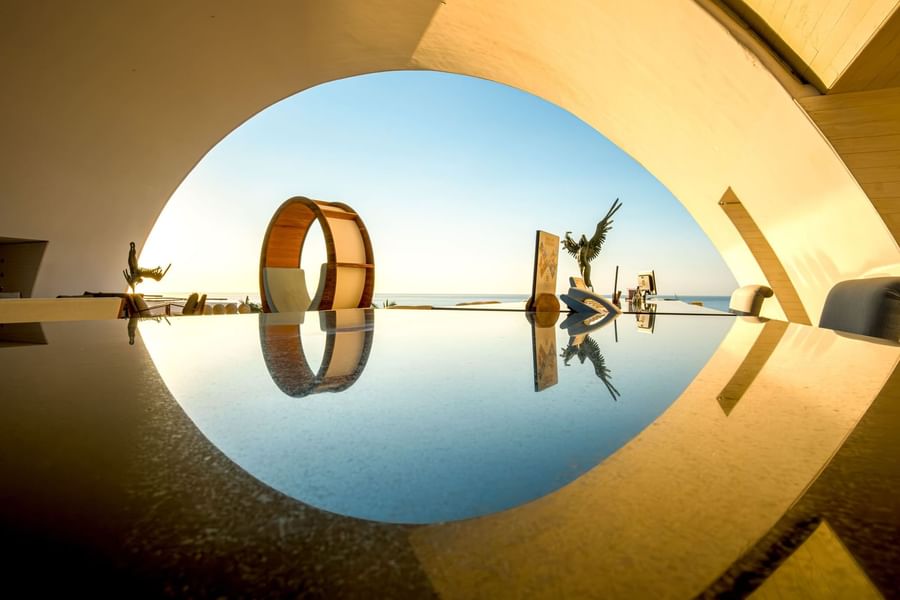 Sculptures beautifully reflected in a tranquil pool, showcasing the artistic architecture of Marquis Los Cabos Resort