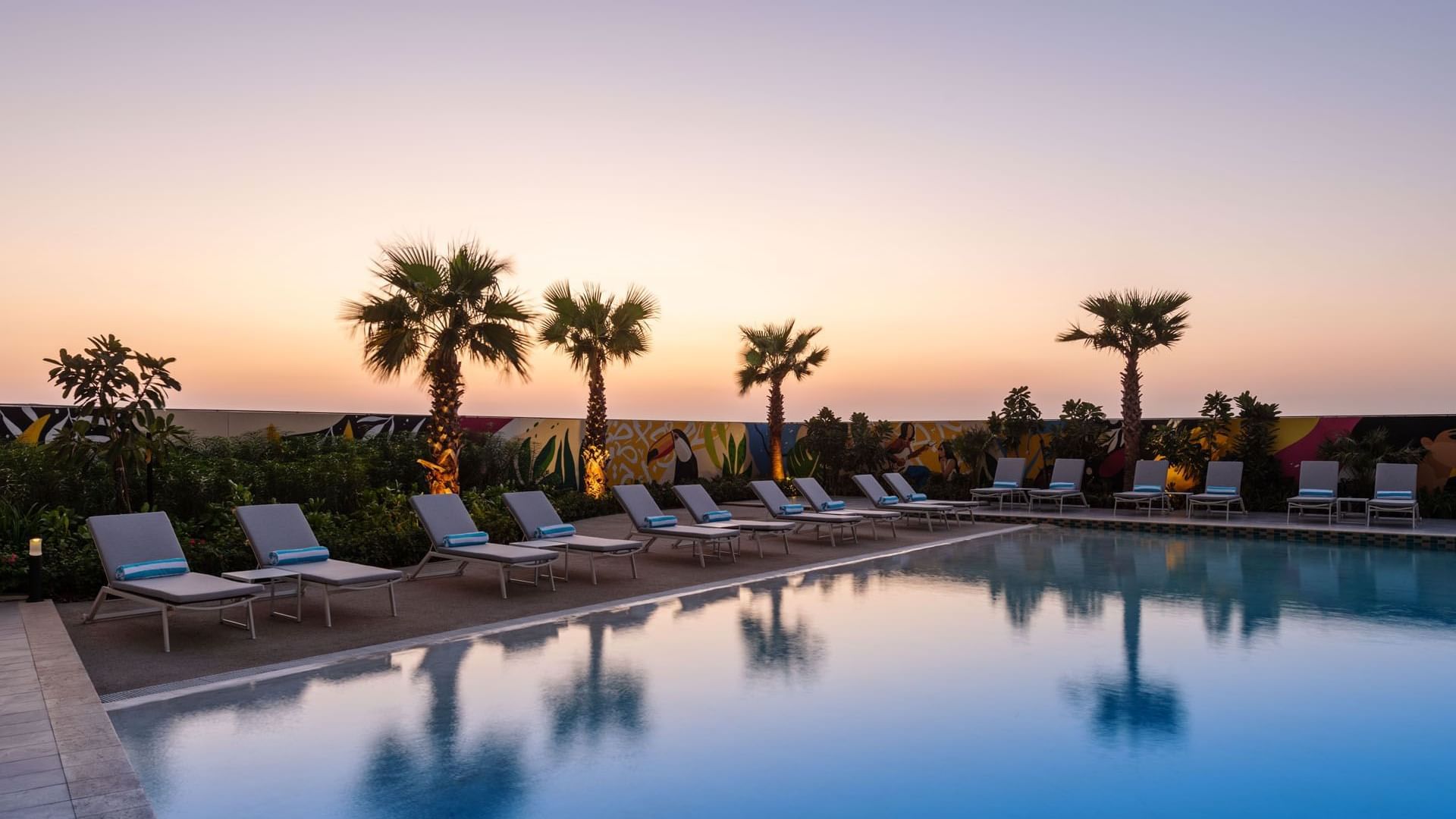 Outdoor pool with sunbeds in DAMAC Maison Aykon City Hotel Apartments at sunset