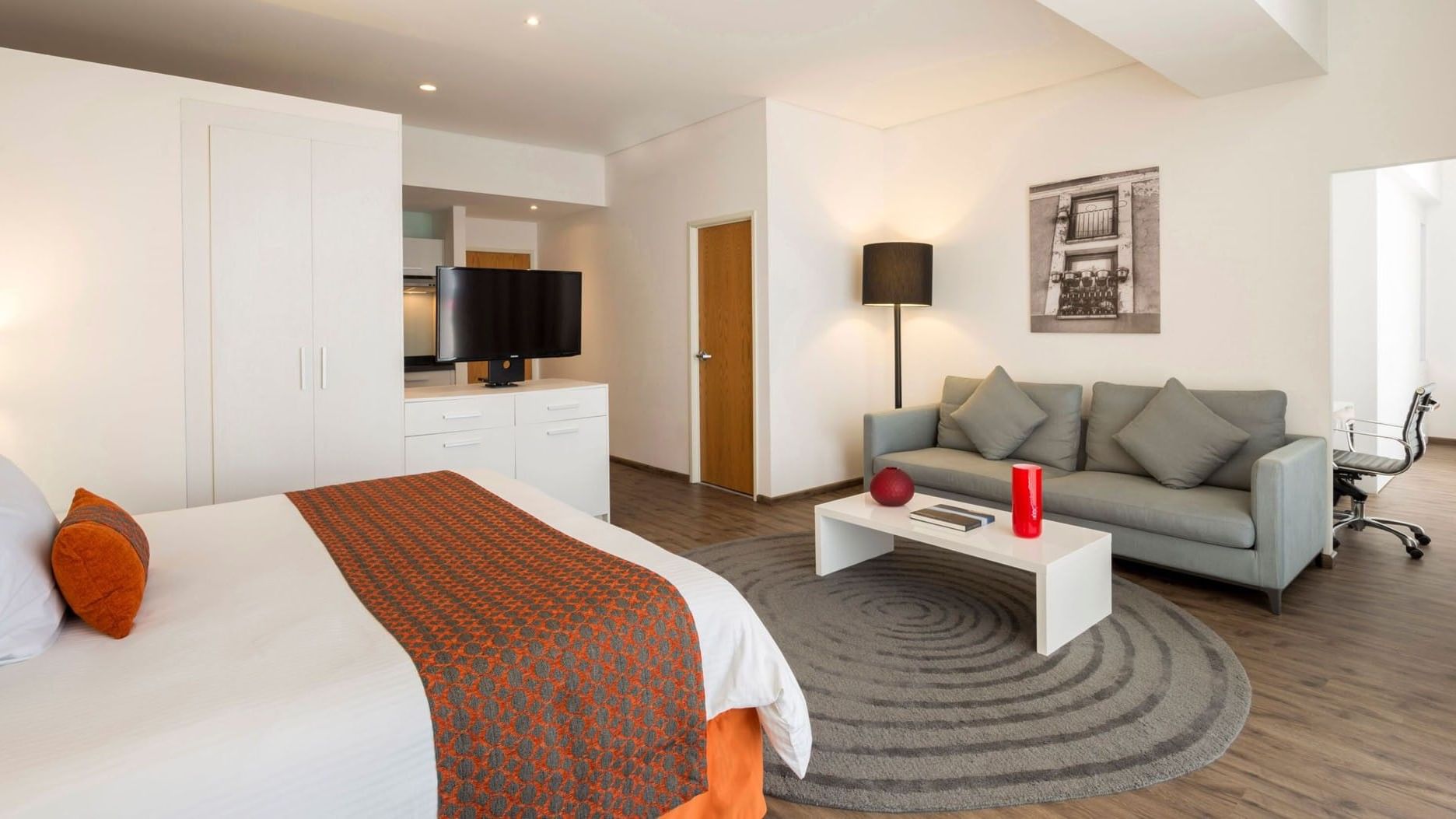 King Junior Suite at Camino Real Puebla Angelopolis featuring a grey sofa, a round rug, and a wall-mounted TV