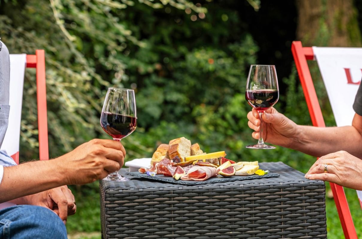 Couple toasting wine over a table holding a charcuterie board at The Lounge Bar & Terrace in Warwick Reine Astrid - Lyon