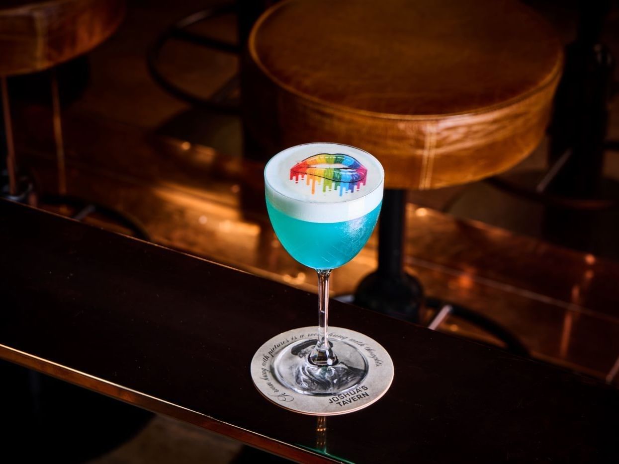 Cocktail «Blue Pride» com um desenho de lábios arco-íris no balcão do bar da Joshida's Tavern.