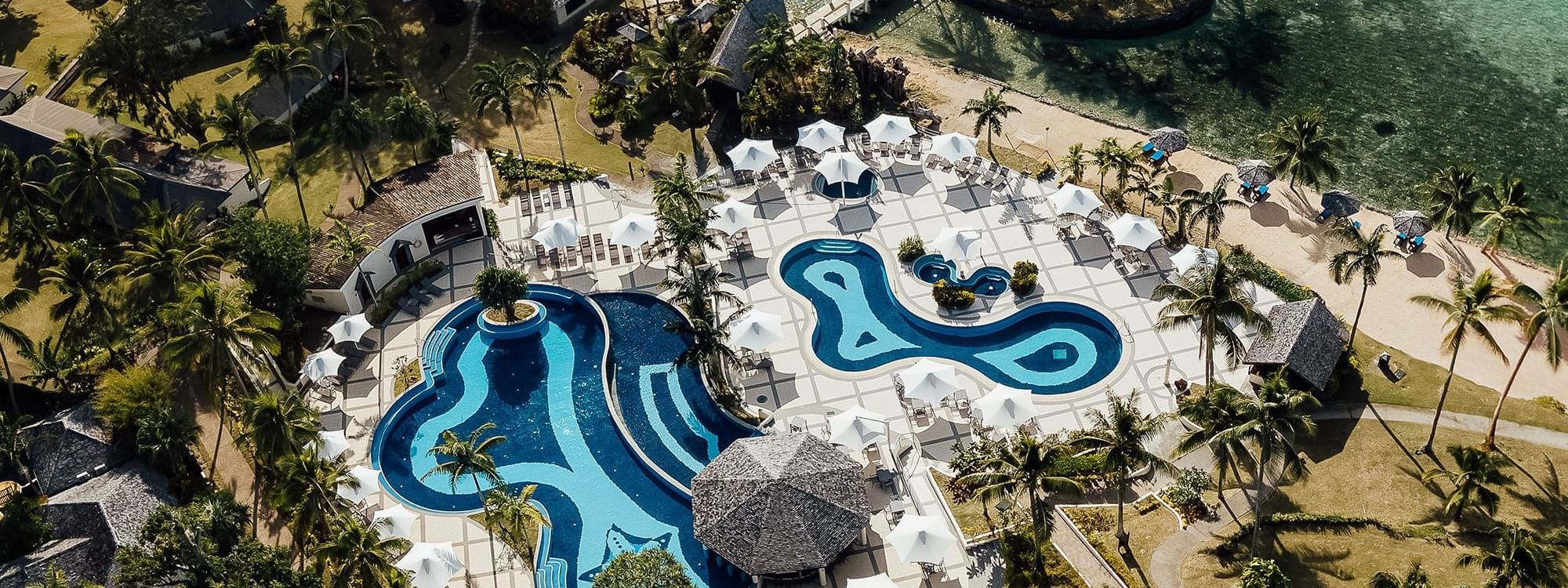 High-angle view of outdoor pool & hotel at Warwick Le Lagon