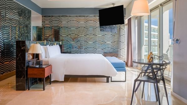 Bed and TV with seating area in Sun and Moon Suite at Live Aqua Beach Resort Cancun