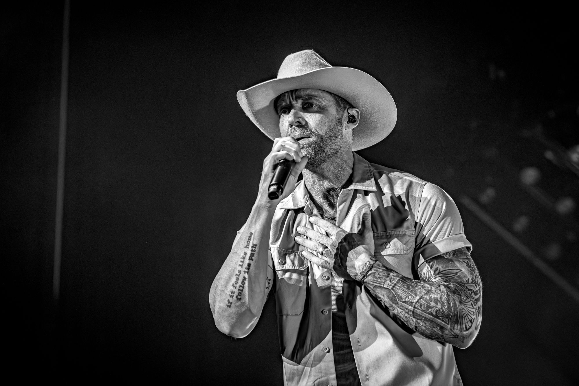 Brett Young wearing a cowboy hat singing into microphone.