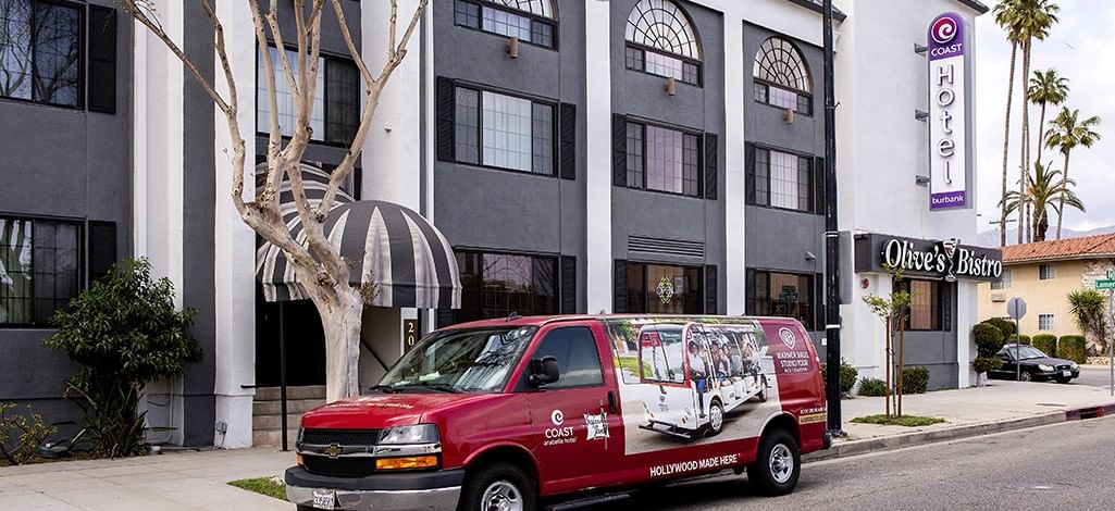 Exterior of Coast Burbank Hotel with the hotel shuttle parked out fron