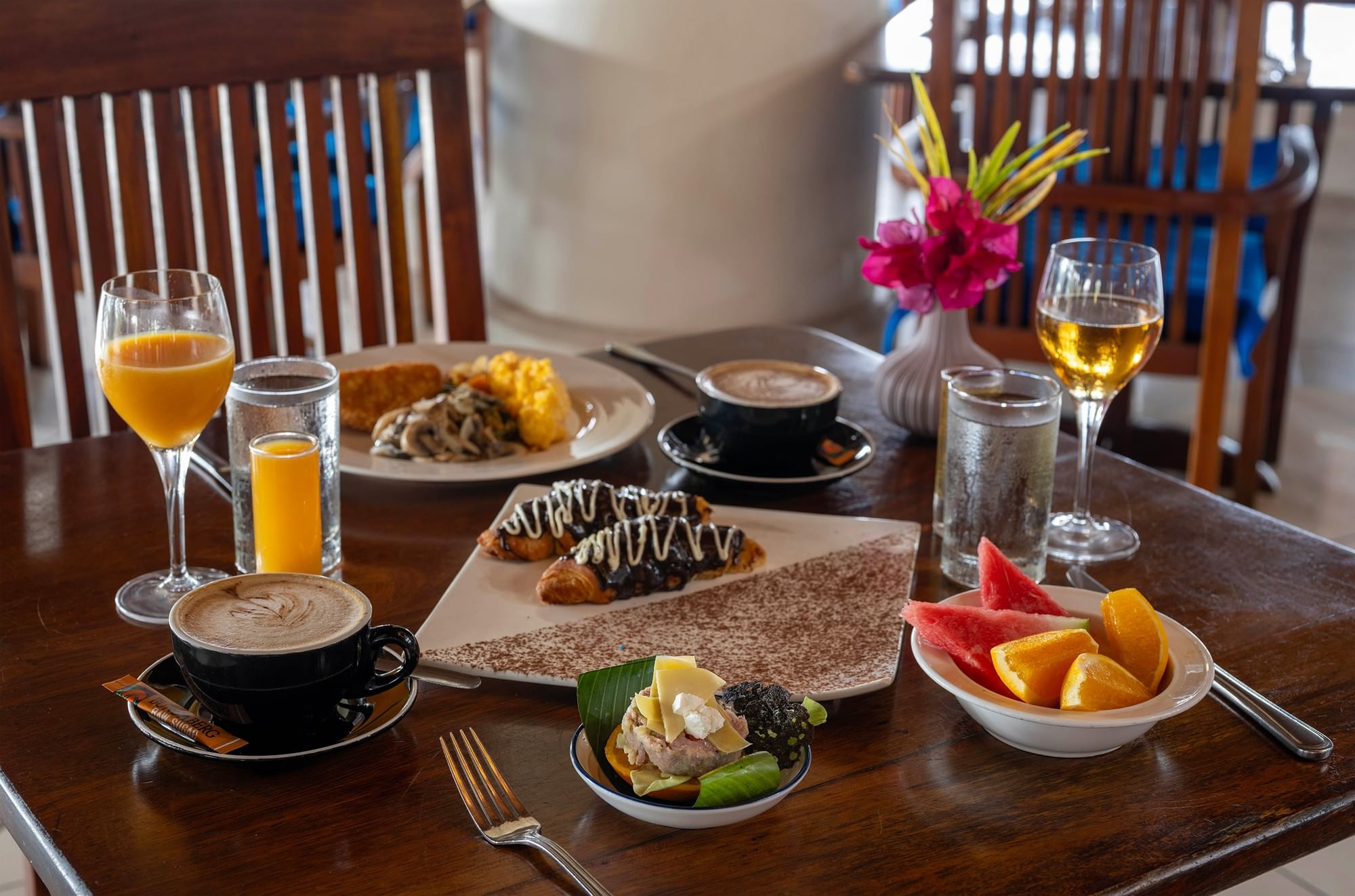 Breakfast spread with pastries, fruits, and drinks on a wooden table at Warwick Le Lagon