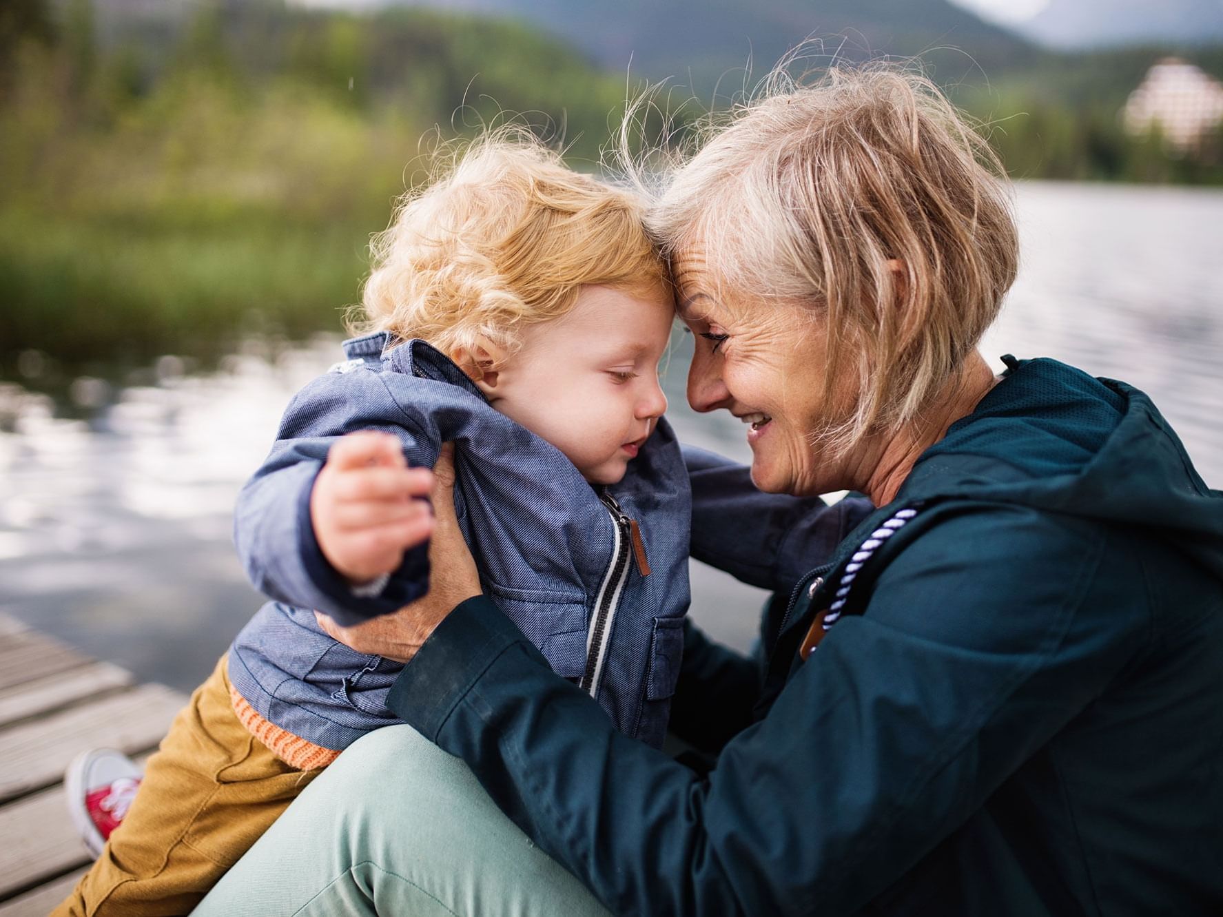 Grandmother and a young child tenderly touching foreheads on a wooden dock near High Peaks Resort