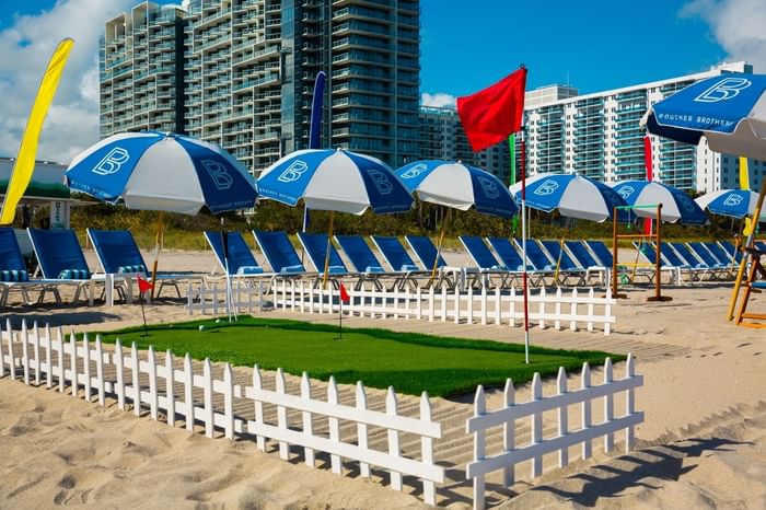 A serene beach with a putting green and sun loungers at The Diplomat Resort