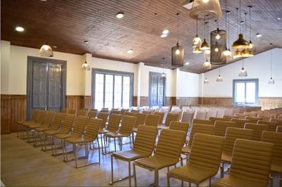 Theater set up by wood-paneled walls under hanging mesh lamps in Carmenere Meeting Room at NOI Blend Colchagua
