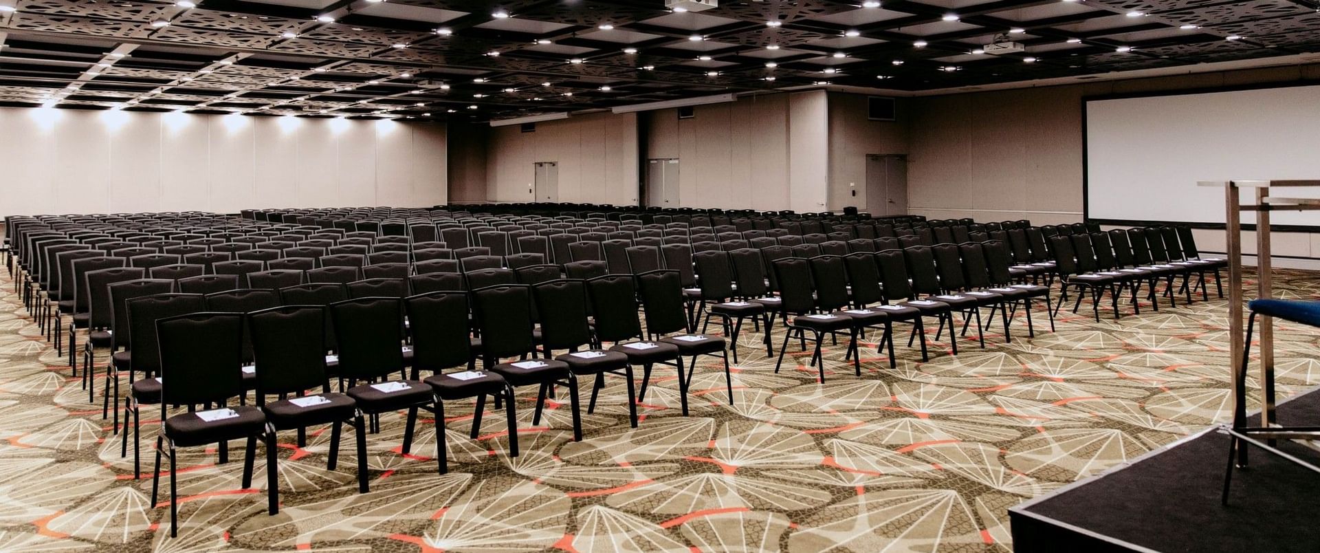 Empty conference room with rows of chairs and a stage at Novotel Sydney Parramatta