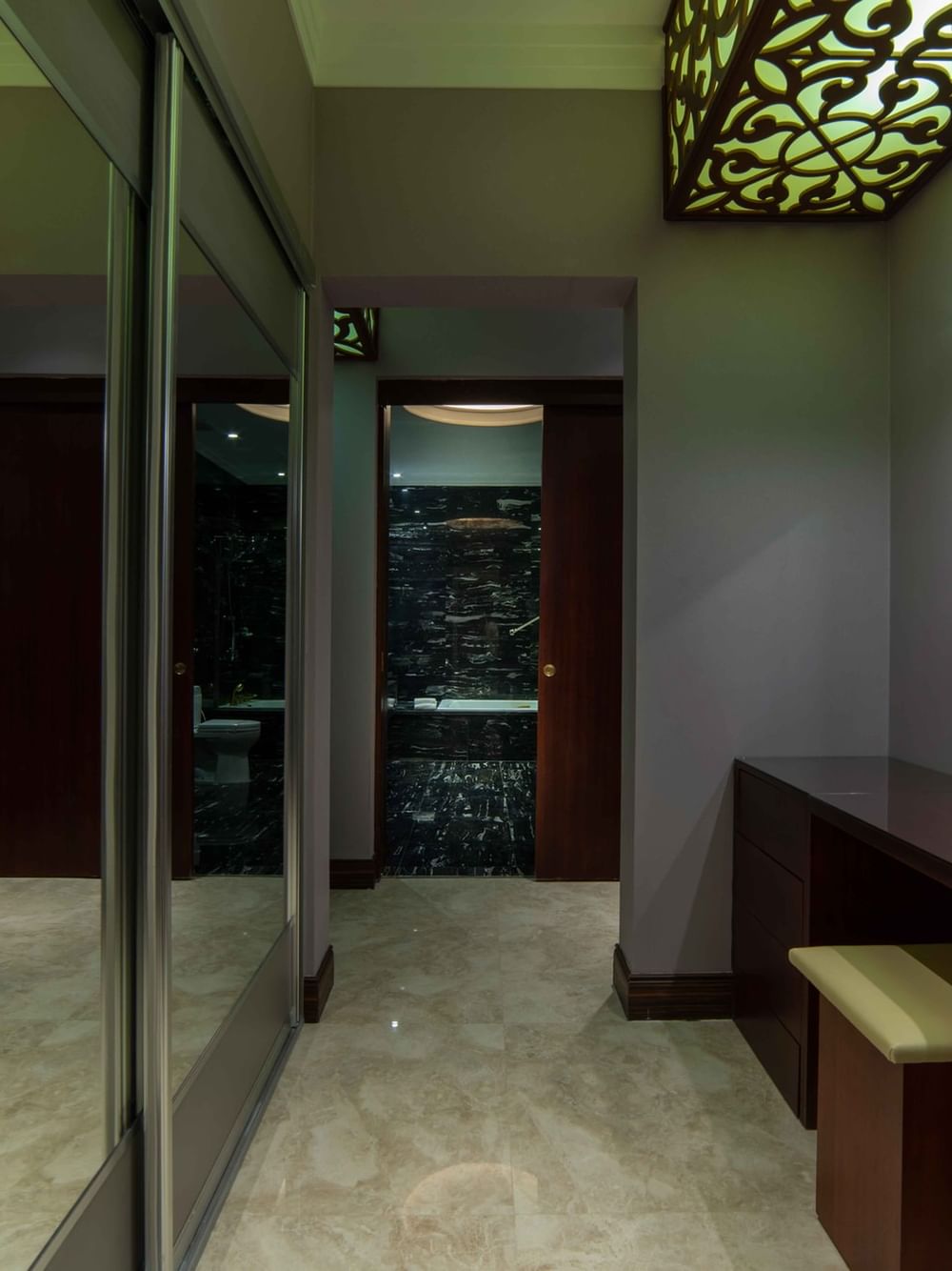 Dark wood vanity and sliding mirror doors under ornate lattice ceiling panels in Penthouse Villa at Warwick Al Khobar