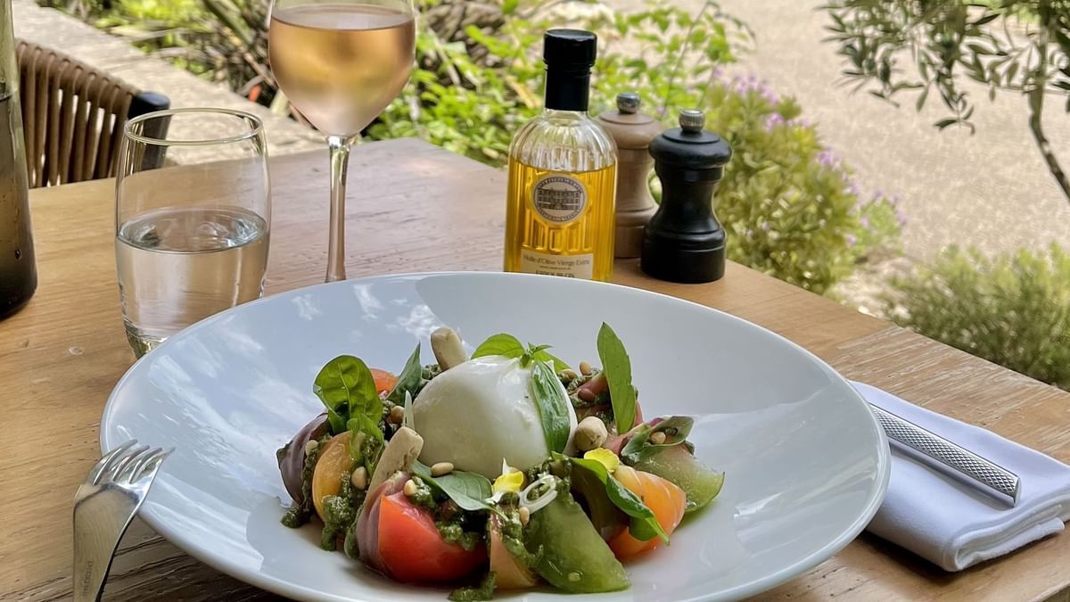Assiette de salade avec vin blanc, huile d'olive et moulin à poivre sur une table en bois.