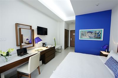A comfortable room at Hotel Mykonos with a king-sized bed and a vibrant blue accent wall