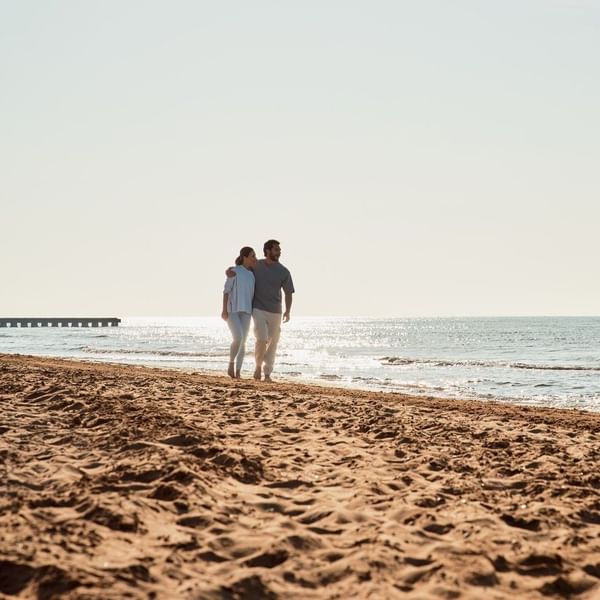 Coppia che passeggia sulla spiaggia al tramonto al Falkensteiner Group