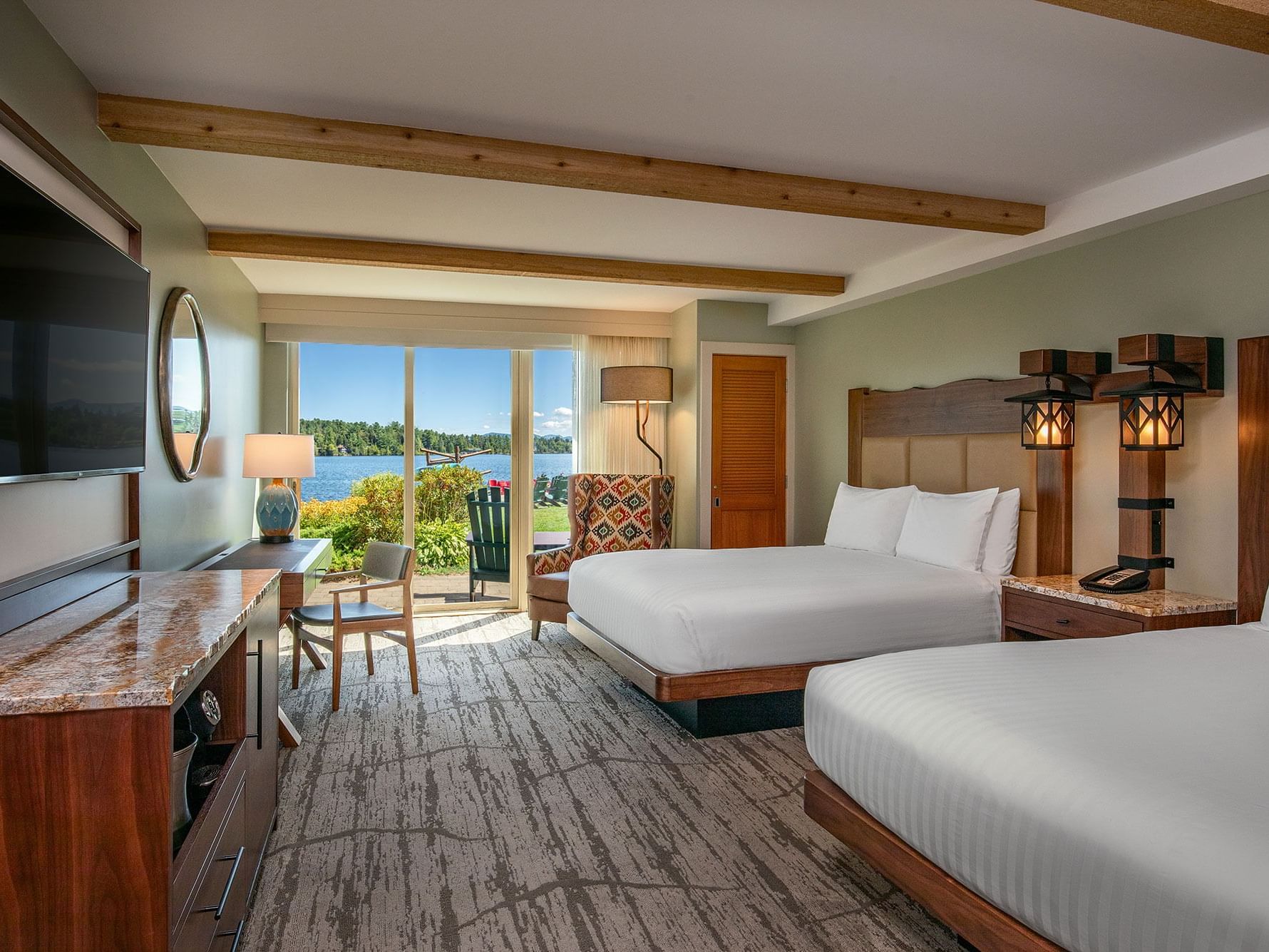 TV with work desk facing the bed and couch by the window in Lake View Queen at High Peaks Resort