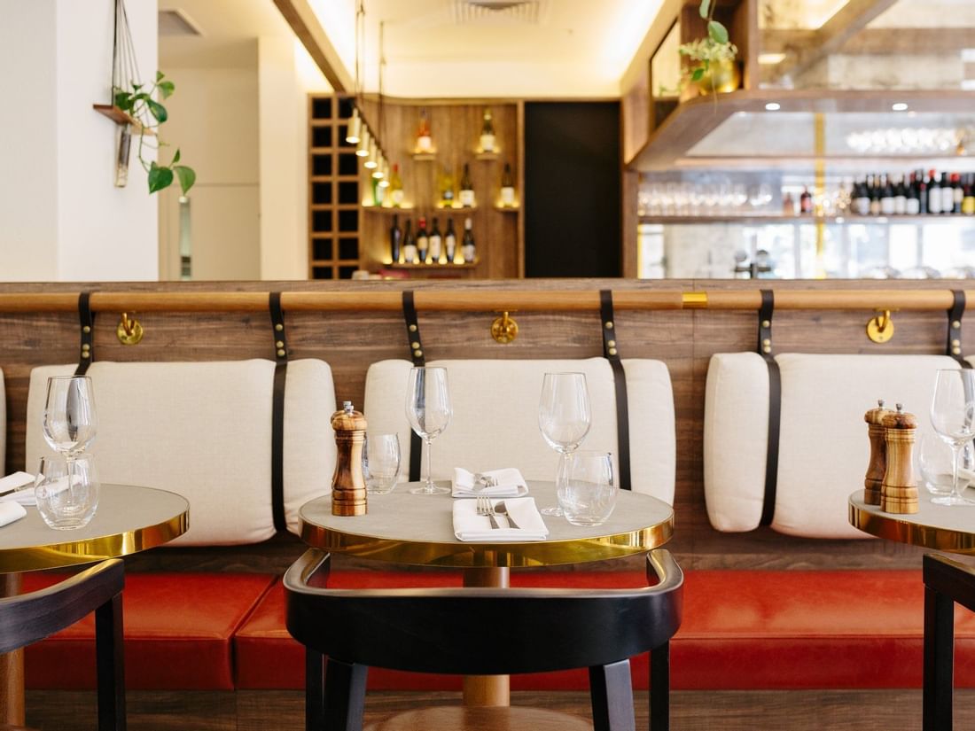 Modern, stylish banquette seating and small round tables set with glasses inside The Croft House at The Sebel Brisbane
